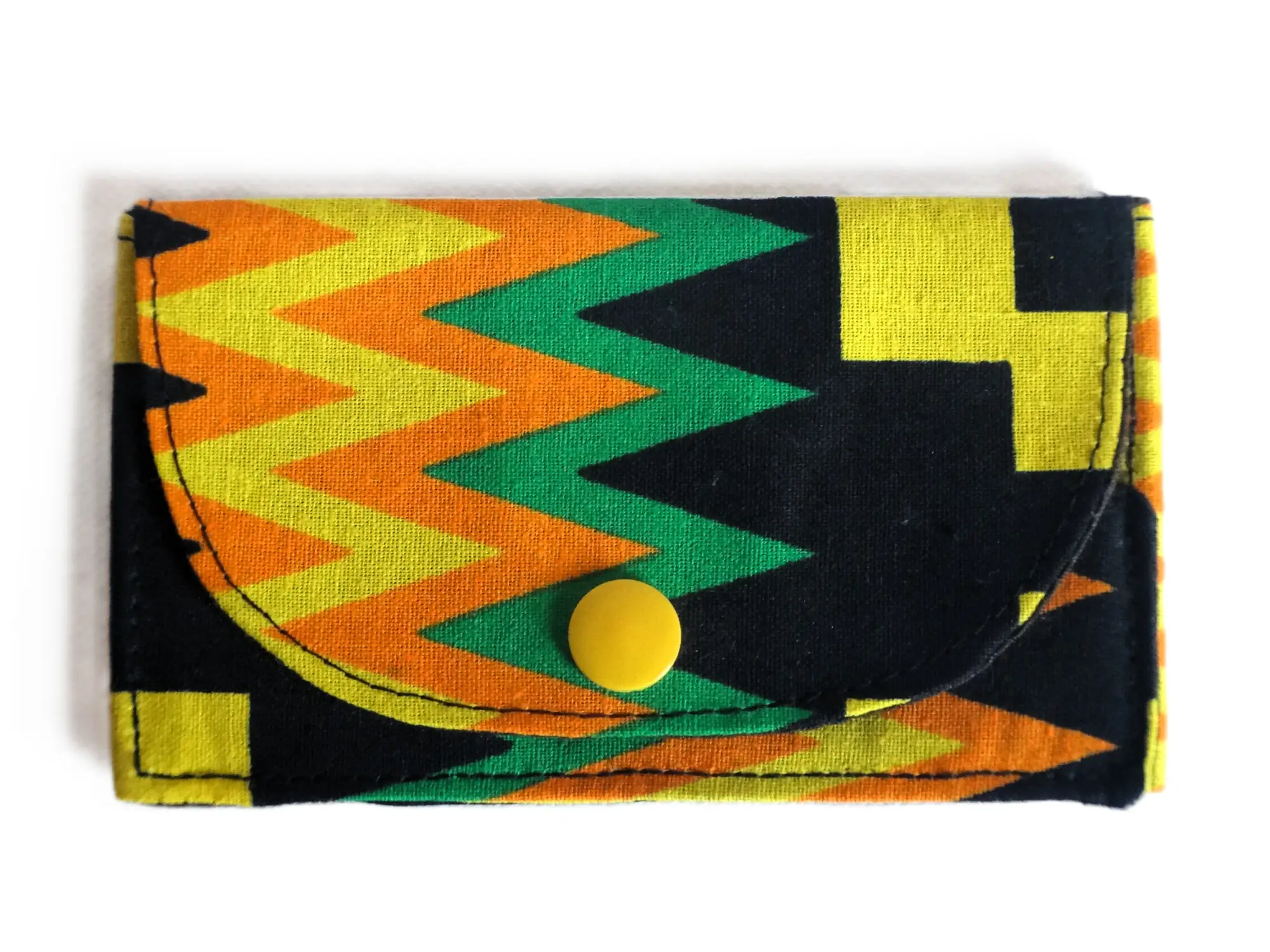 Pequeño monedero de tela de la marca MARTIU con cierre de botón a presión amarillo, diseñado con un patrón de zig-zag y bloques de color negro y amarillo que caracteriza la línea artesanal de esta colección.