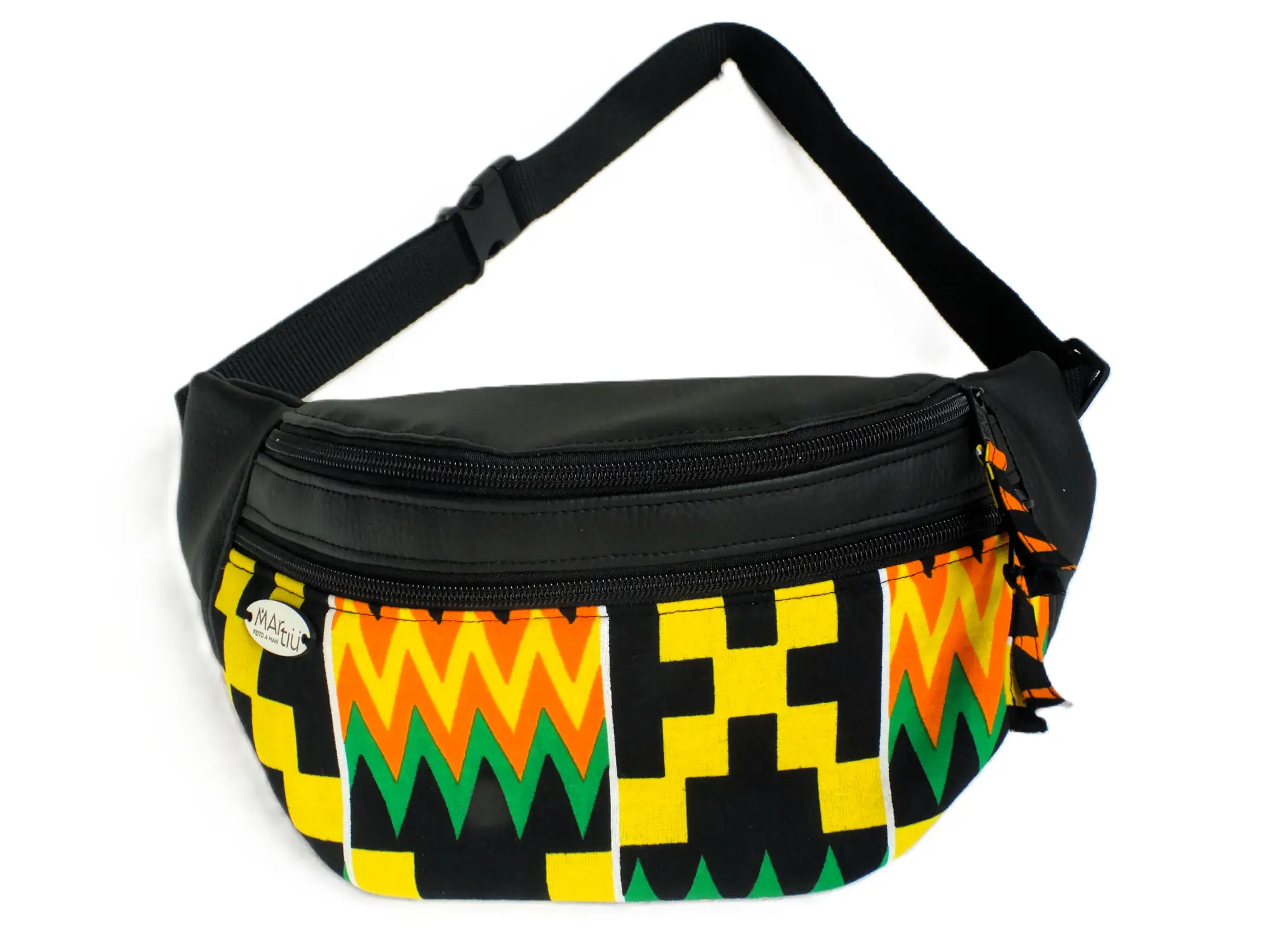 Riñonera artesanal de la marca MARTIU fabricada en cuero negro con un panel frontal de tela con estampado geométrico en amarillo, verde y naranja, destacando por su diseño funcional y la etiqueta metálica distintiva de la marca.