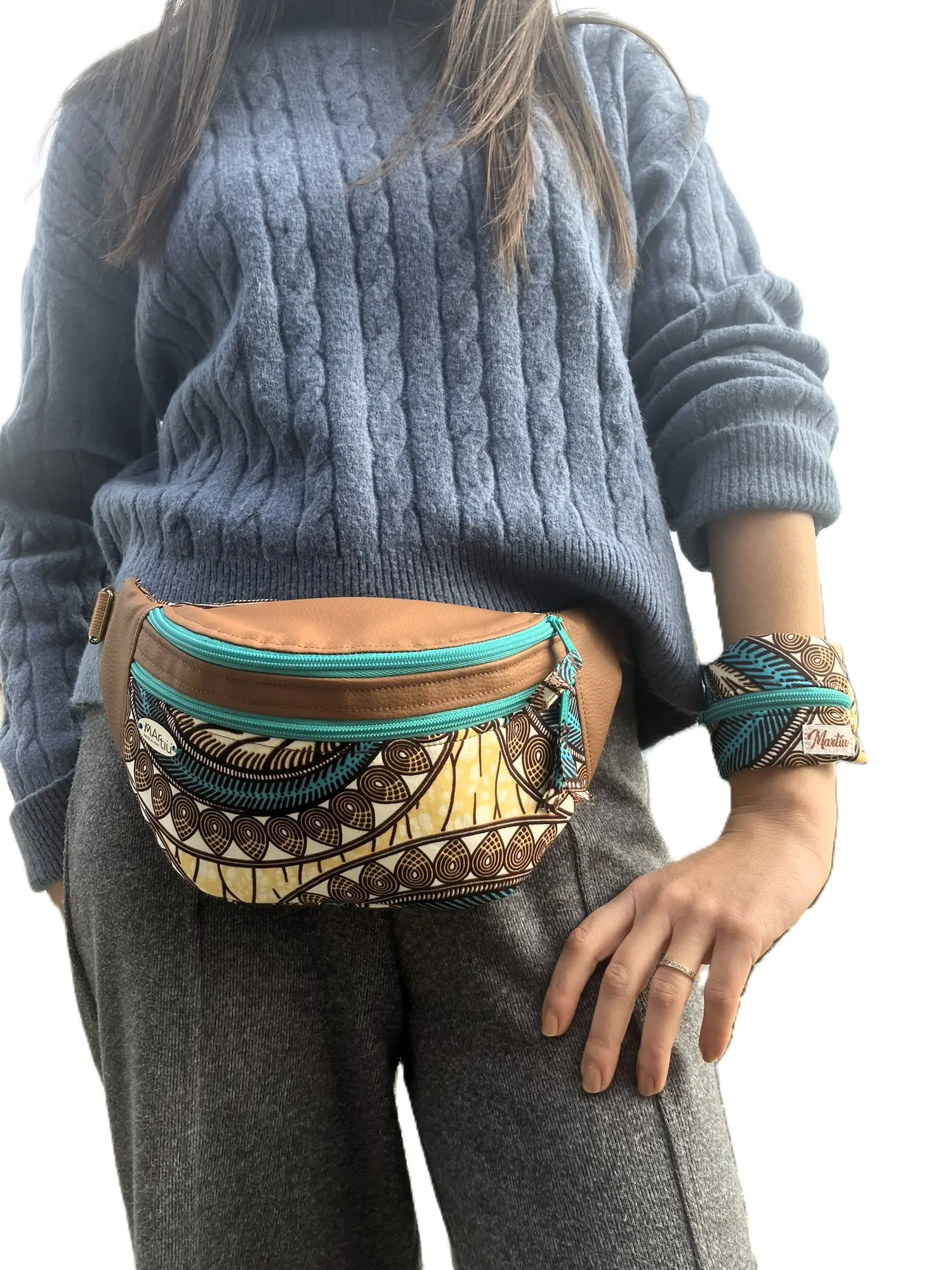 Una modelo luce una riñonera de MARTIU en cuero marrón combinada con tela estampada y una pulsera monedero a juego en la muñeca, resaltando la versatilidad de los complementos de la marca.