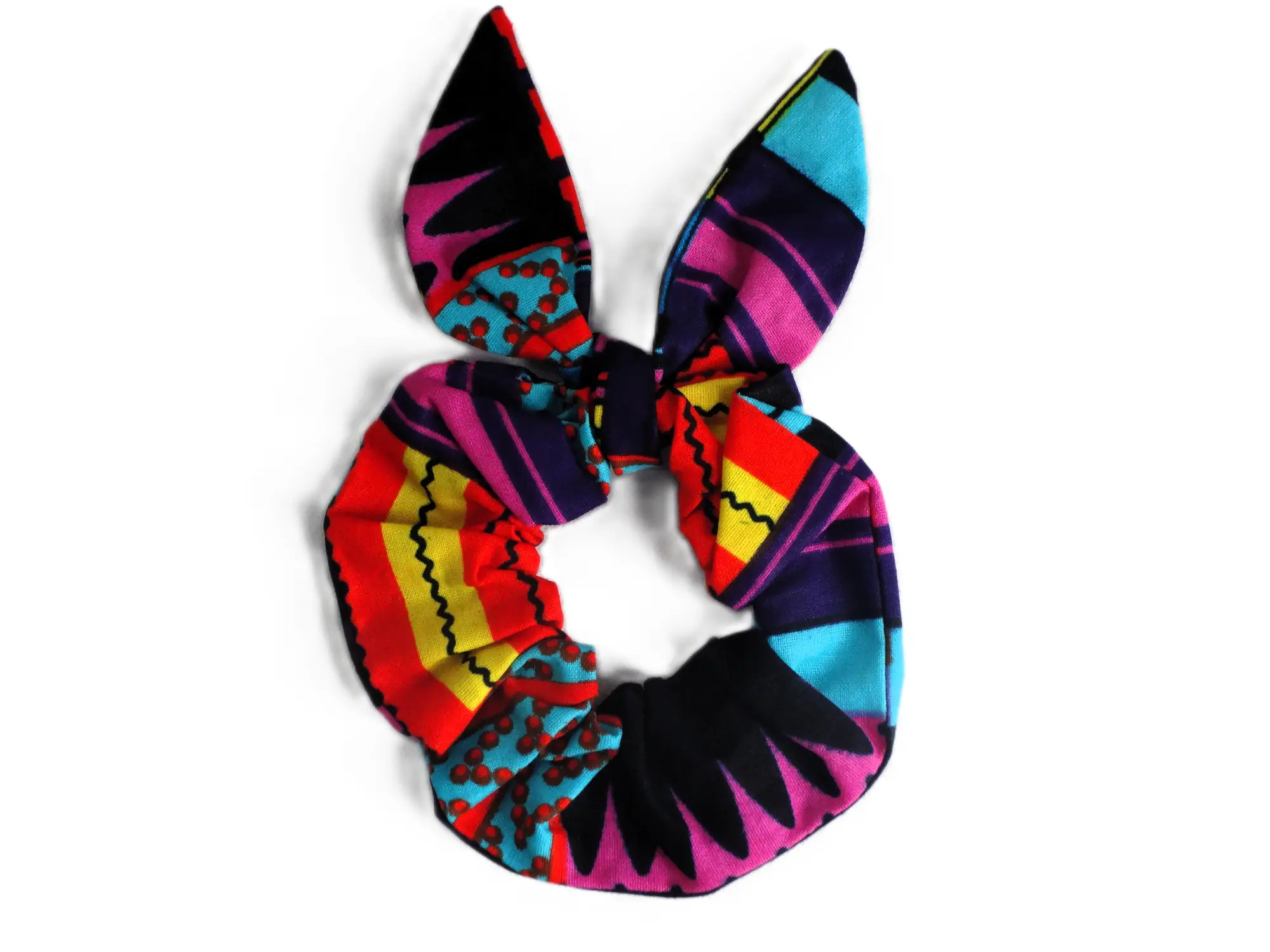 Accesorio para el cabello de MARTIU consistente en un coletero con diseño de lazo, que utiliza los motivos geométricos y colores vibrantes de la marca para un acabado artesanal y original.