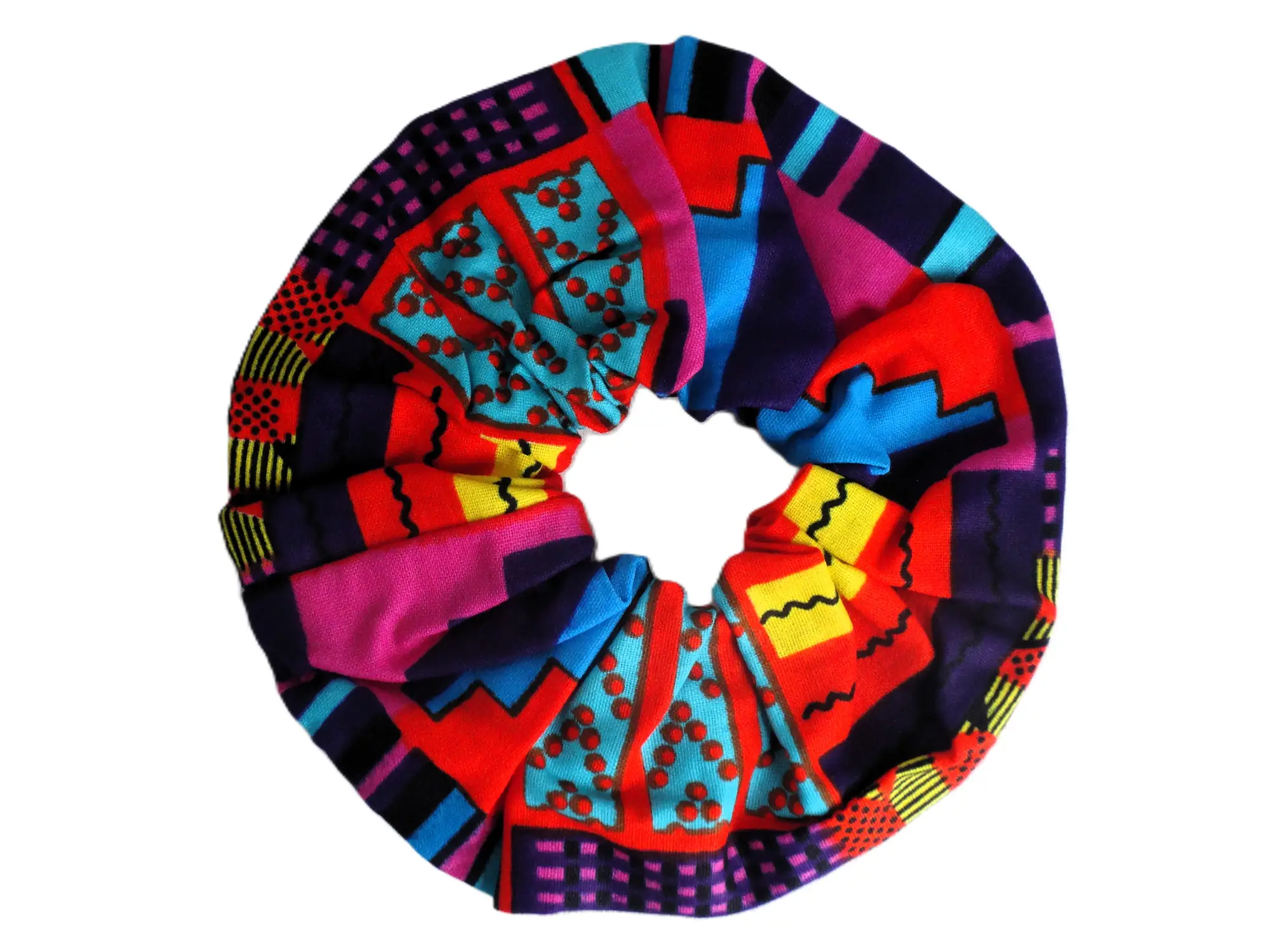 Coletero elástico de la marca MARTIU elaborado con retales de tela de la colección, presentando un diseño circular con patrones de puntos y formas geométricas en colores saturados.