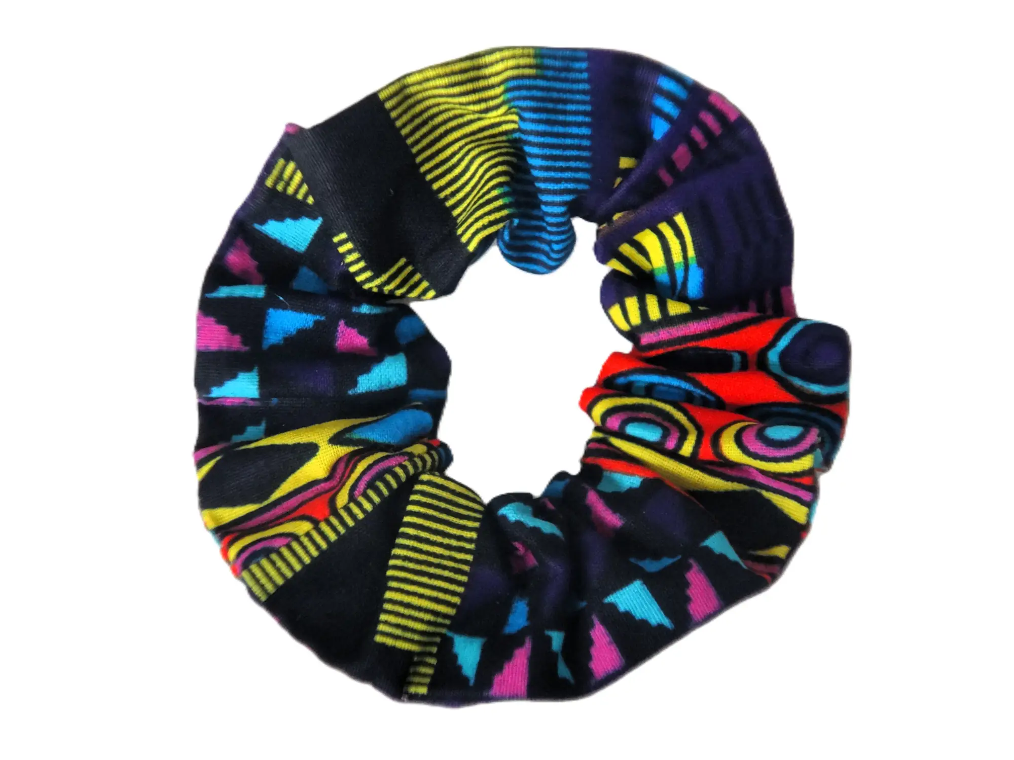 Coletero de tela de la marca MARTIU que combina patrones de rayas amarillas y azules con bloques negros y fucsias, un accesorio de autor que complementa la estética artesanal de la marca.