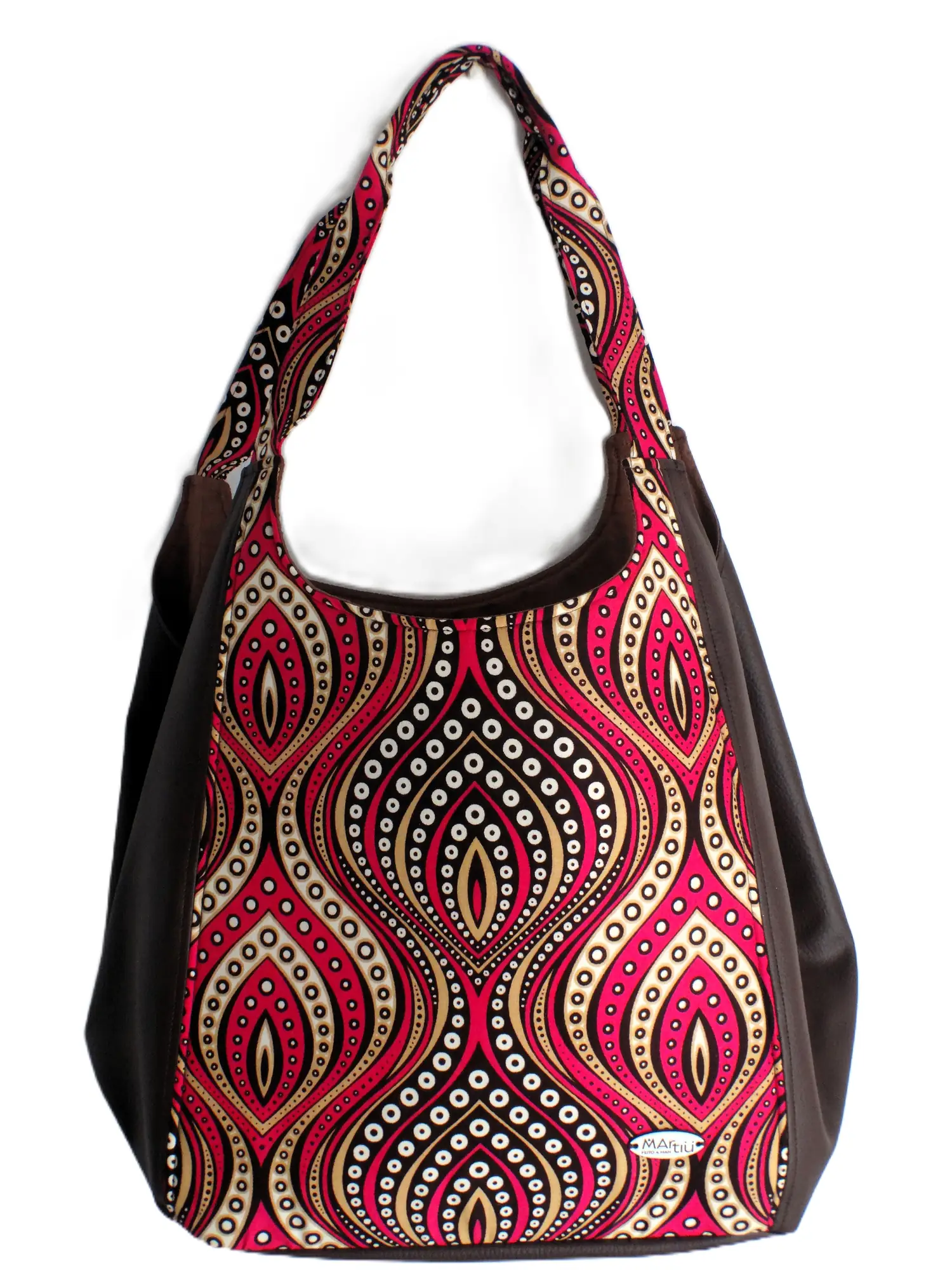 Bolso de gran capacidad de la marca MARTIU con laterales de cuero marrón oscuro y un cuerpo central de tela artesanal con patrones geométricos en fucsia y crema, diseñado para combinar funcionalidad y estilo de autor.
