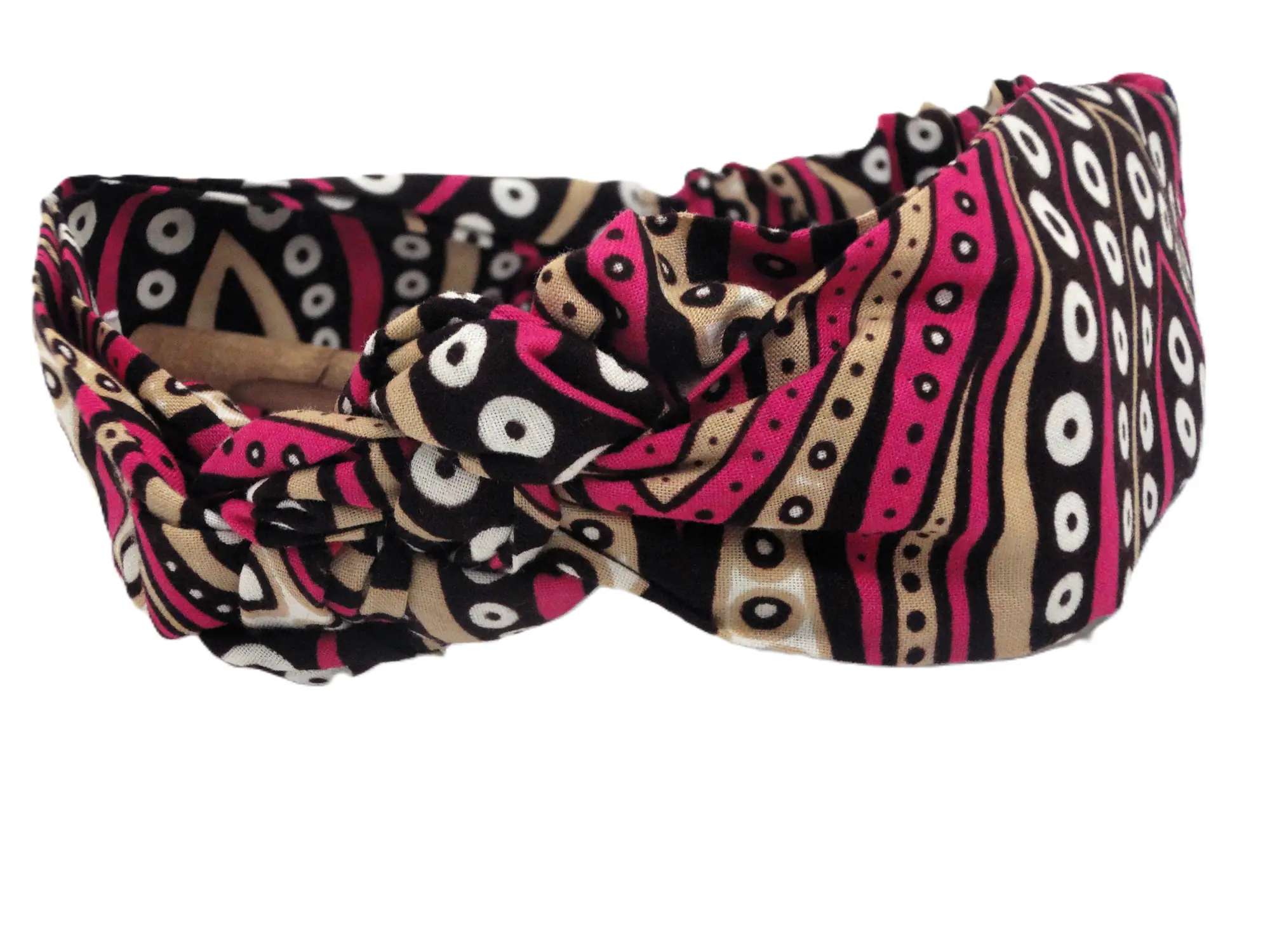 Primer plano de una diadema tipo turbante con nudo central de la marca MARTIU, confeccionada con tela de algodón artesanal que presenta un patrón de puntos y ondas en fucsia, negro y beige.
